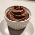 A single serving of rich, dark brown Keto Creamy Chocolate Cheesecake Mousse piped into a white ramekin.