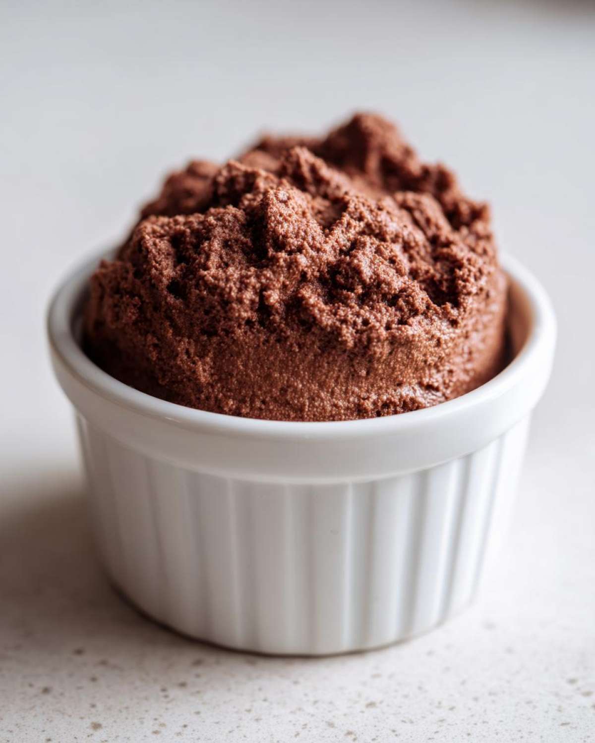 A single serving of rich, airy Keto Creamy Chocolate Cheesecake Mousse in a white fluted ramekin.
