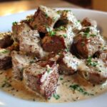 Close-up of seared Keto Creamy Peppercorn Steak Bites smothered in a rich, creamy sauce and garnished with parsley.