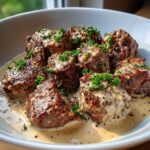 Close-up of seared Keto Creamy Peppercorn Steak Bites smothered in a rich, creamy sauce with visible peppercorns.