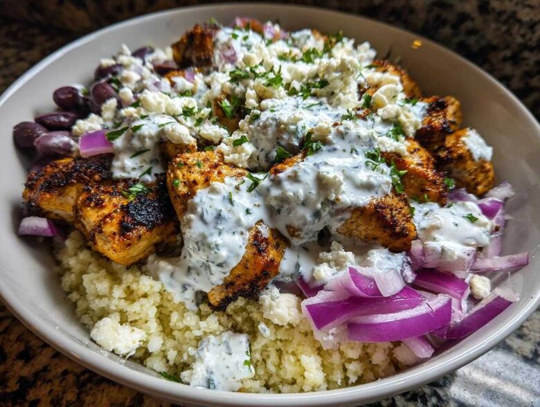 Close-up of Keto Greek Chicken Bowls with Tzatziki, featuring seasoned chicken, cauliflower rice, feta, and red onion.