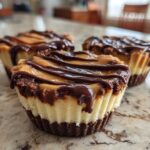 Three decadent No-Bake Chocolate Peanut Butter Cheesecake Cups topped with peanut butter and chocolate drizzle.
