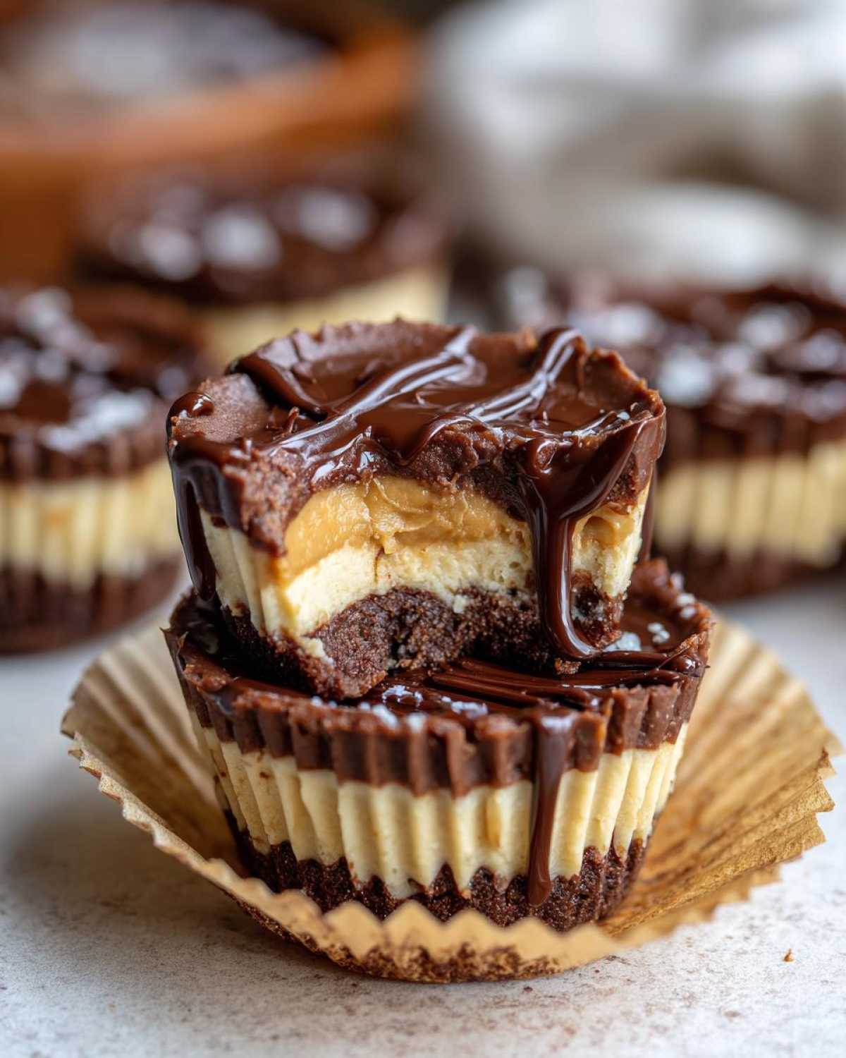 Two stacked No-Bake Chocolate Peanut Butter Cheesecake Cups, one cut open showing layers of chocolate crust, cheesecake, and peanut butter filling.