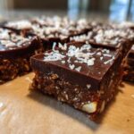 Close-up of fudgy No-Bake Coconut Chocolate Date Bars topped with shredded coconut.