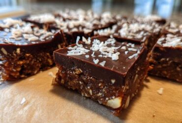 Close-up of fudgy No-Bake Coconut Chocolate Date Bars topped with shredded coconut.