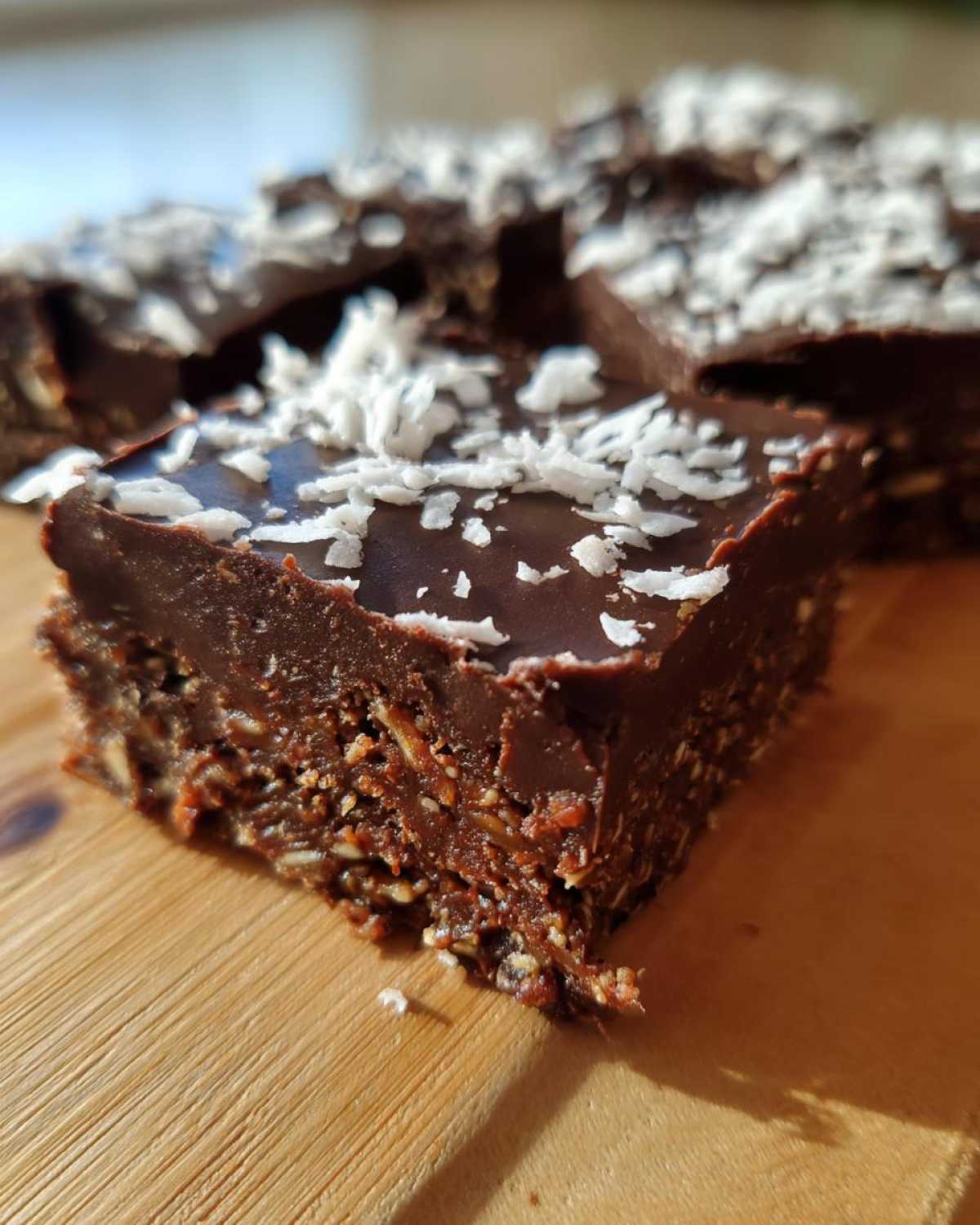 A close-up of a fudgy No-Bake Coconut Chocolate Date Bars square topped with shredded coconut.