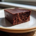 A single, thick square of rich, dark No-Bake Espresso Chocolate Fudge on a light ceramic plate.