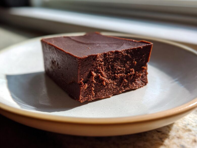 A single, thick square of rich, dark No-Bake Espresso Chocolate Fudge on a light ceramic plate.