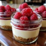 Close-up of No-Bake Raspberry White Chocolate Cheesecake Jars topped with fresh raspberries.
