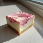 A single square of No-Bake Strawberry Lemon Cheesecake Bars with a graham cracker crust and swirled topping.