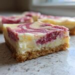 A close-up of a square No-Bake Strawberry Lemon Cheesecake Bars showing a graham cracker crust and a swirled berry topping.