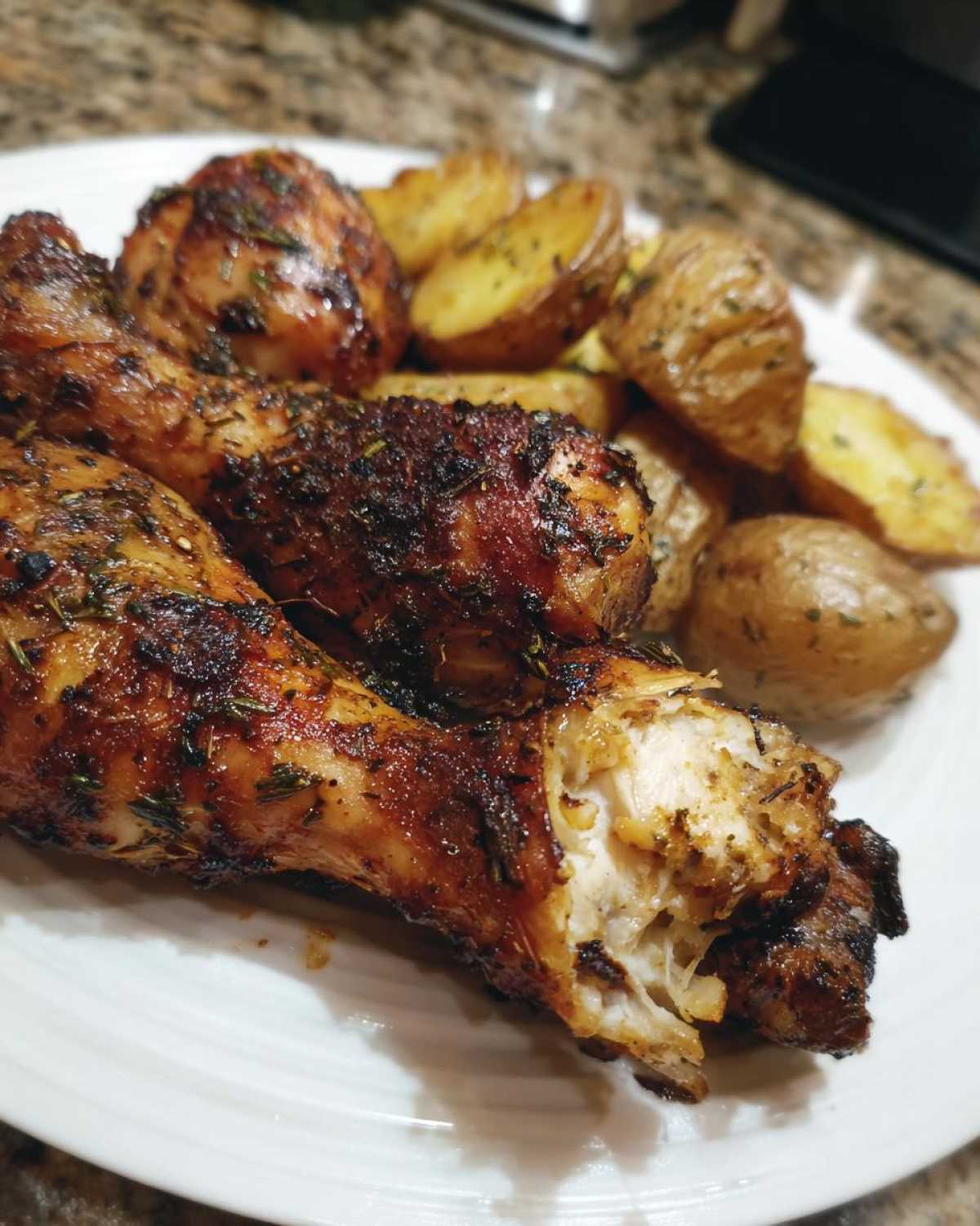 Close-up of juicy Sheet Pan Garlic Parmesan Chicken Drumsticks with roasted potatoes on a white plate.