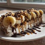 Thick Vegan Chocolate Peanut Butter Banana Smoothie Bowl topped with banana slices, granola, and chocolate drizzle.