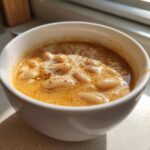 Close-up of a white bowl filled with Vegan Creamy Lemon Garlic White Bean Soup, topped with spices.