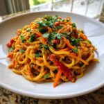 A close-up of a serving of Vegan Creamy Peanut Noodle Salad tossed with shredded carrots and topped with fresh cilantro.