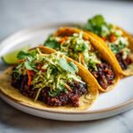 Three Vegan Easy Black Bean Tacos filled with dark seasoned black beans and topped with bright cilantro lime slaw.
