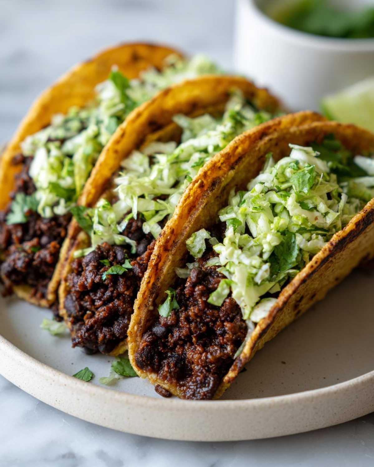 Three crispy tacos filled with seasoned black beans and topped with bright, shredded cilantro lime slaw.
