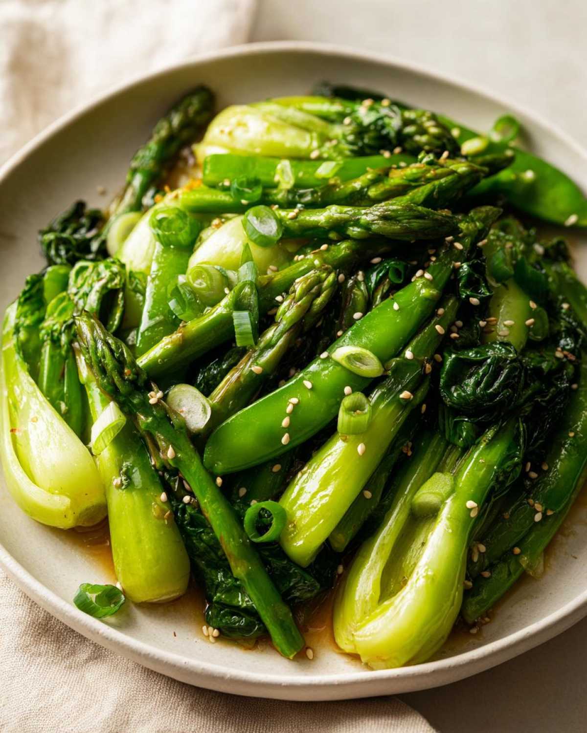 Close-up of bright green Vegan Spring Vegetable Stir Fry with ginger, featuring asparagus, snap peas, and bok choy.