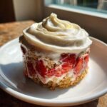 A serving of Vegan Strawberry Cream Overnight Oats layered with fresh strawberries and topped with whipped cream.