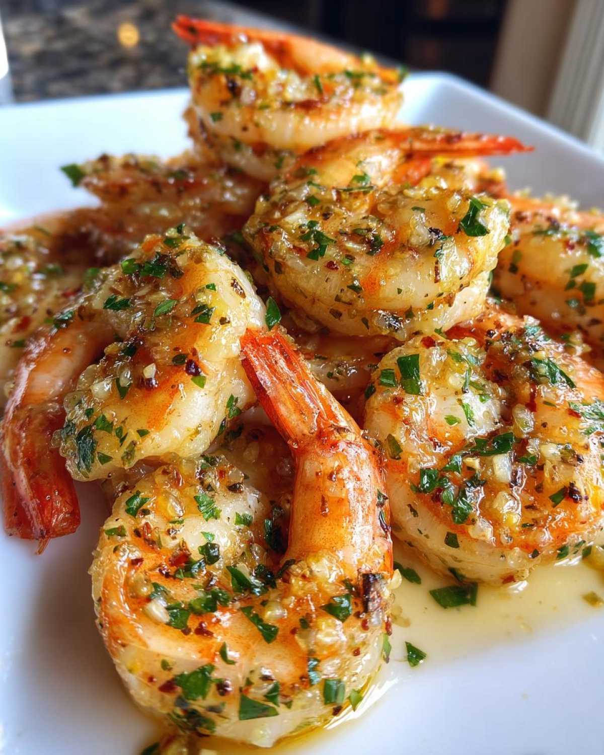 Close-up of plump Air Fryer Crispy Garlic Butter Shrimp glistening with butter sauce and herbs.