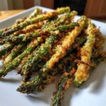 Close-up of Air Fryer Crispy Parmesan Asparagus Fries piled on a white plate.