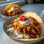 Close-up of Air Fryer Crispy Turkey Taco Bowls featuring seasoned ground turkey, rice, cheese, sour cream, and salsa on a tortilla.