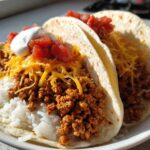 Two soft tortillas filled with seasoned ground turkey, white rice, shredded cheese, salsa, and sour cream, ready to eat as Air Fryer Crispy Turkey Taco Bowls.