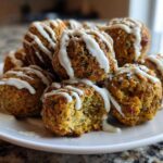 A pile of golden Air Fryer Herb Falafel Balls drizzled generously with white tahini sauce on a white plate.
