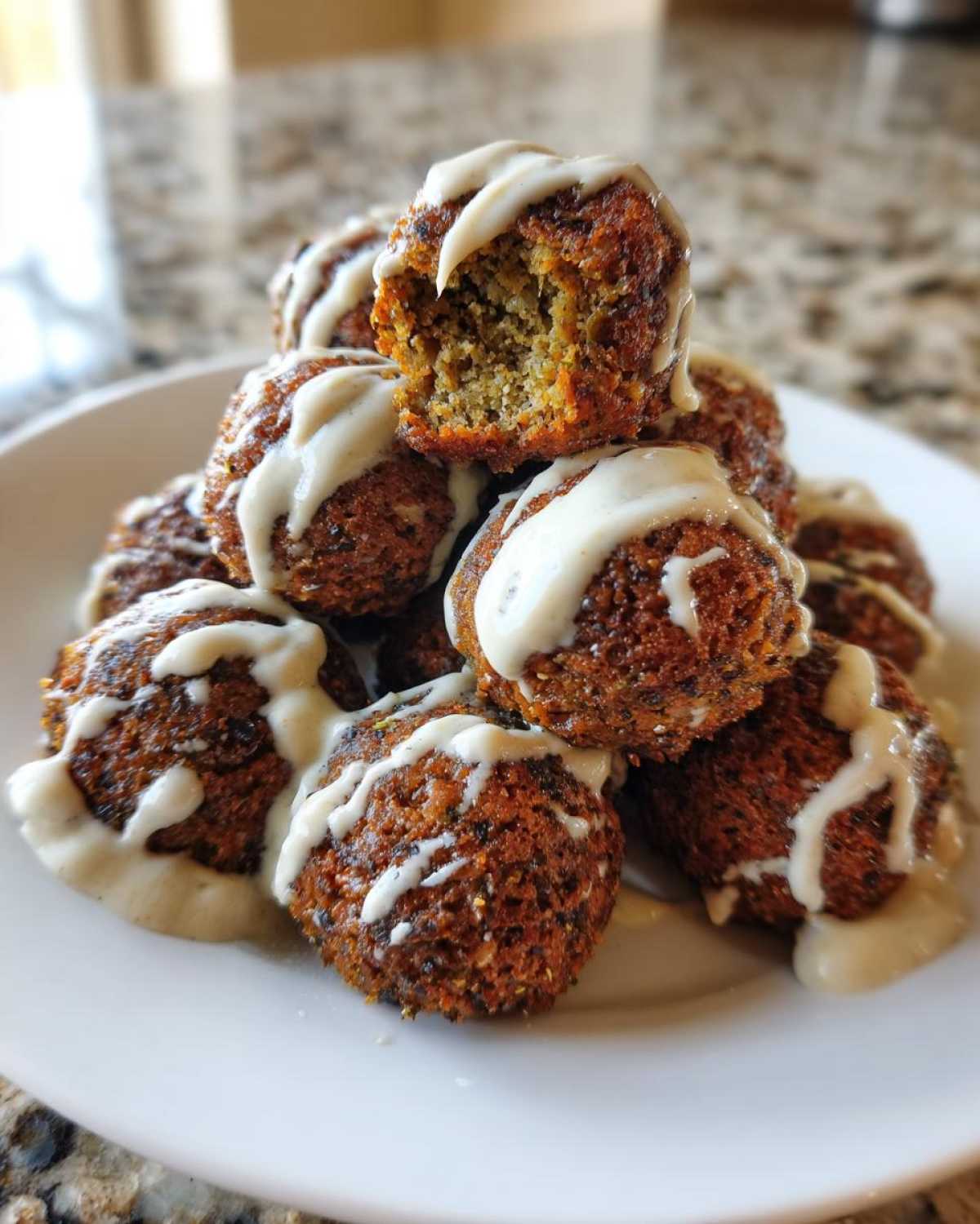 A pile of crispy Air Fryer Herb Falafel Balls drizzled generously with creamy tahini sauce.