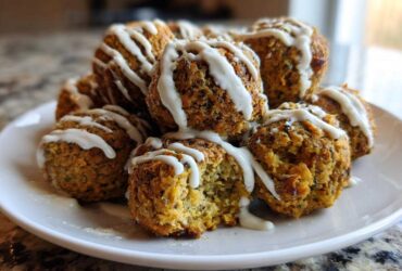 A pile of golden Air Fryer Herb Falafel Balls drizzled generously with white tahini sauce on a white plate.