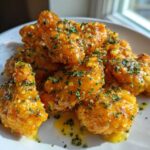 Close-up of crispy chicken wings generously coated in glossy Copycat Garlic Parmesan Wing Sauce and sprinkled with parsley.