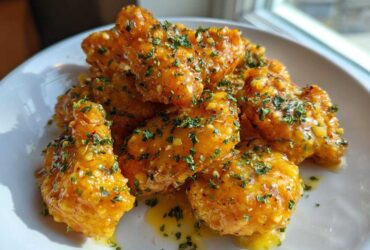 Close-up of crispy chicken wings generously coated in glossy Copycat Garlic Parmesan Wing Sauce and sprinkled with parsley.