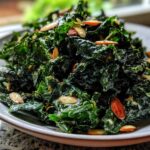 A close-up of a bowl of Copycat Kale Crunch Salad coated in creamy dressing and topped with sliced almonds.