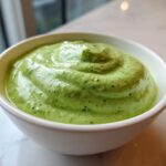 Close-up of a creamy, vibrant green Easy 5-Minute Salsa Verde Yogurt Dip swirled in a small white bowl.