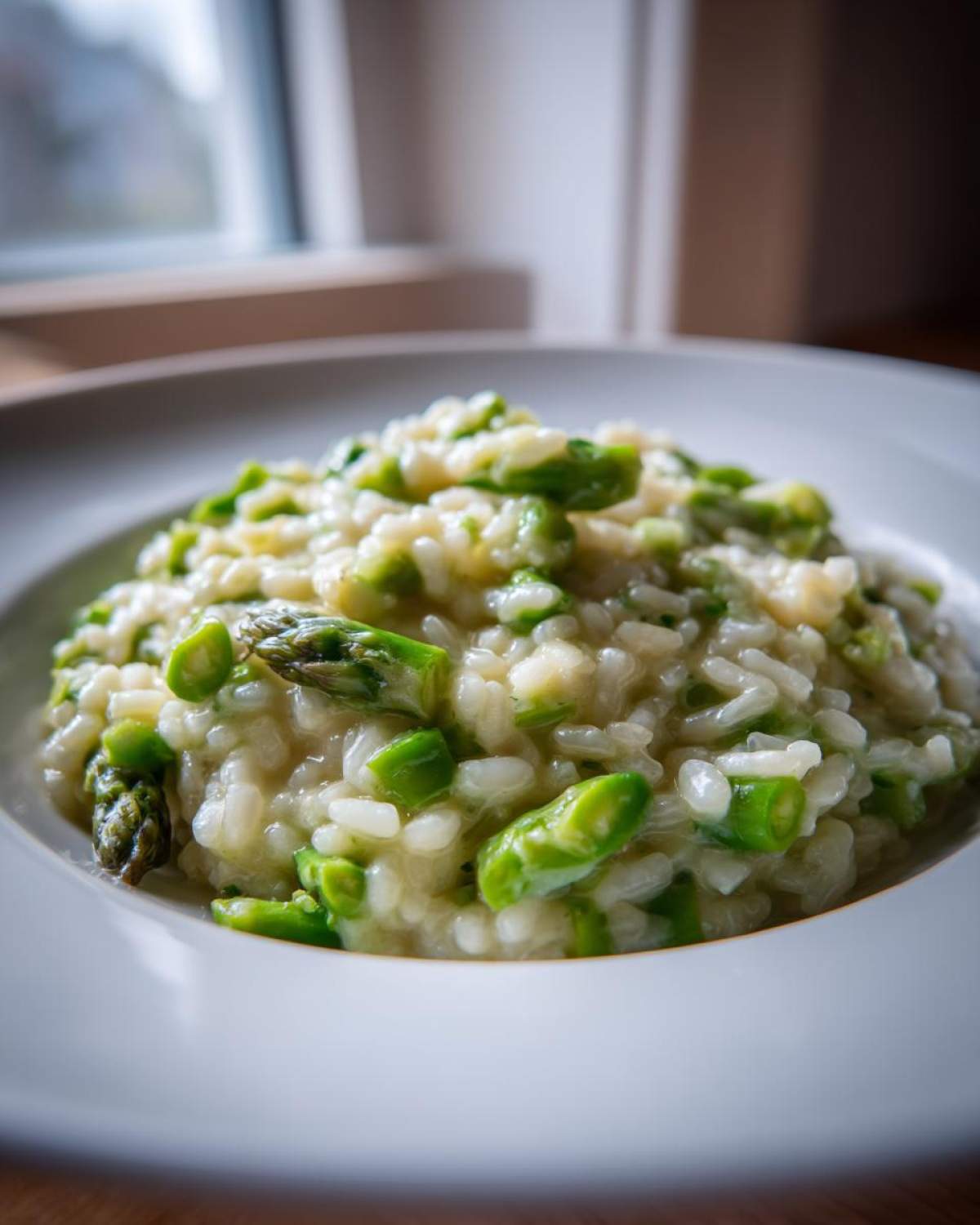 A close-up, appetizing shot of Easy Creamy Asparagus Risotto served in a white bowl.