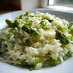 A close-up shot of a serving of Easy Creamy Asparagus Risotto, featuring bright green asparagus tips mixed into creamy white rice.