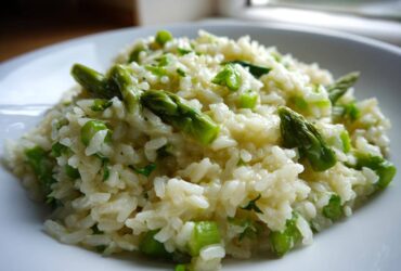 A close-up shot of a serving of Easy Creamy Asparagus Risotto, featuring bright green asparagus tips mixed into creamy white rice.