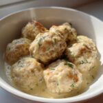 Close-up of Easy Creamy Greek Chicken Meatballs served in a white bowl with a rich, creamy dill sauce.