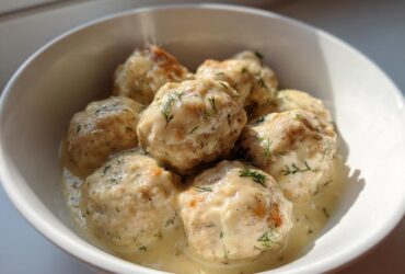 Close-up of Easy Creamy Greek Chicken Meatballs served in a white bowl with a rich, creamy dill sauce.