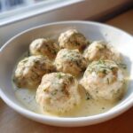 Six Easy Creamy Greek Chicken Meatballs served in a white bowl with a rich, creamy sauce and topped with fresh dill.
