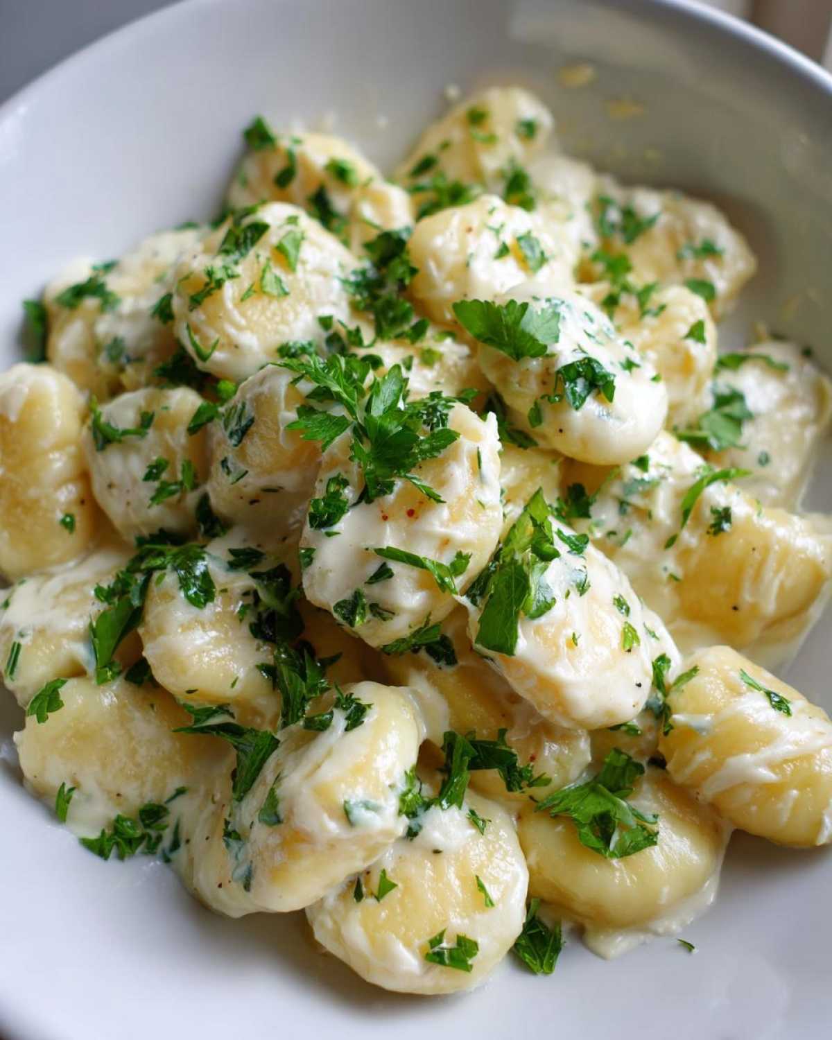 Close-up of Easy One-Pan Creamy Garlic Butter Gnocchi coated in a rich white sauce and topped with fresh parsley.