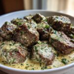 Close-up of seared steak bites smothered in a creamy garlic sauce with visible parsley.