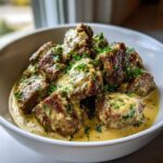 Close-up of Easy One-Pan Creamy Garlic Steak Bites coated in a rich, yellow garlic sauce and sprinkled with fresh parsley.