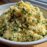 A close-up of fluffy Easy One-Pot Creamy Lemon Herb Couscous topped with fresh parsley and lemon zest in a white bowl.