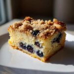 Close-up of a square slice of Easy Sheet Pan Blueberry Streusel Pancake with visible blueberries and crumb topping.
