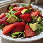 A vibrant bowl of Easy Strawberry Avocado Salad featuring bright red strawberries, creamy avocado chunks, and mixed greens.