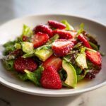 Close-up of a vibrant Easy Strawberry Avocado Salad featuring sliced strawberries, avocado chunks, and mixed greens lightly coated in vinaigrette.