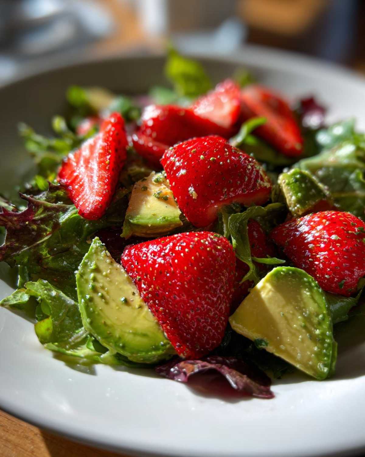 Close-up of a vibrant Easy Strawberry Avocado Salad with sliced strawberries and avocado on mixed greens.
