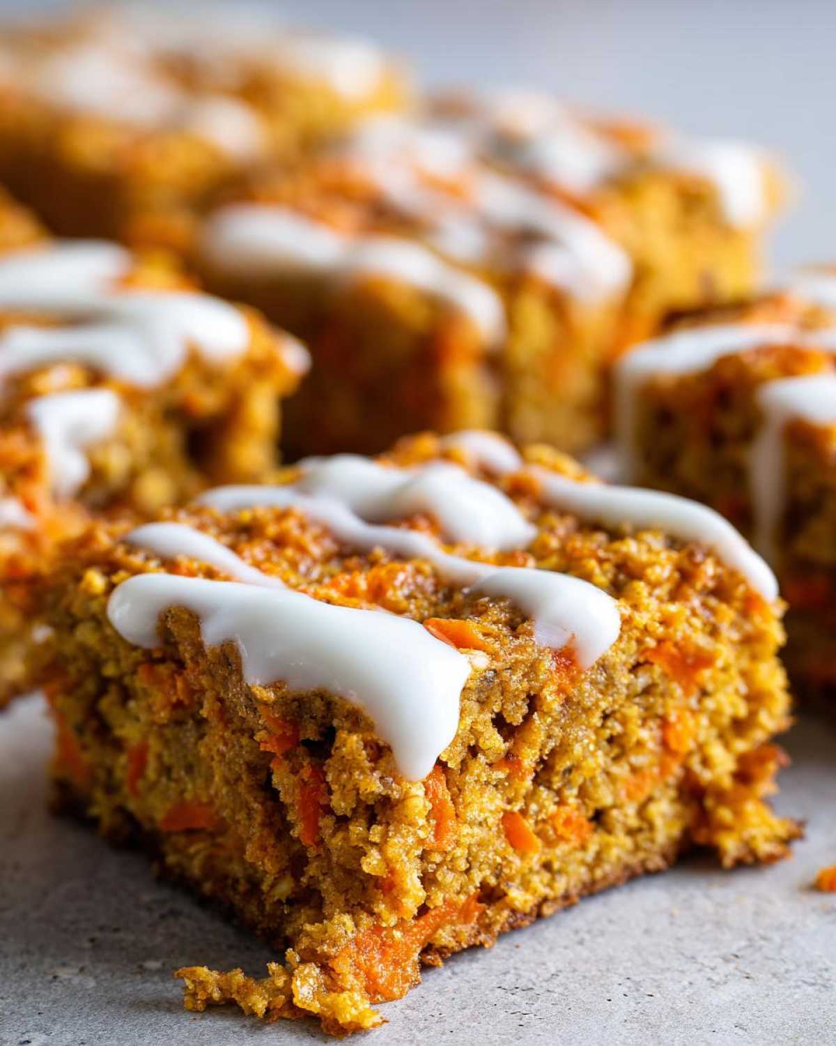 Close-up of a square slice of Gluten-Free Carrot Cake Baked Oats topped with white icing drizzle.