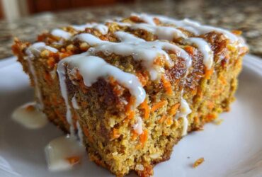 Close-up of a moist slice of Gluten-Free Carrot Cake Baked Oats topped with white drizzle icing.